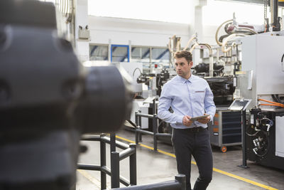 Man with tablet walking in factory shop floor