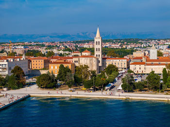 Buildings by sea against sky