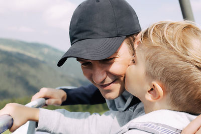 Happy father being kissed by his son while spending a day in nature.