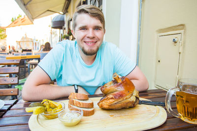 Portrait of happy man having food at table