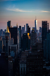Modern buildings in city against sky during sunset