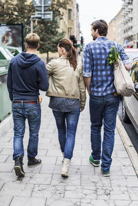 Rear view of friends walking together on sidewalk