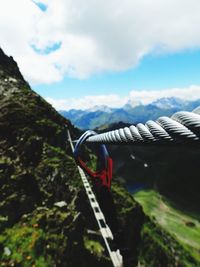 Close-up of rope hanging on mountain against sky