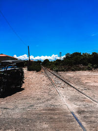 Railroad tracks by road against clear blue sky