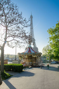 Carousel on street by eiffel tower against clear sky