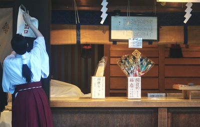 Rear view of woman hanging sign outside shop