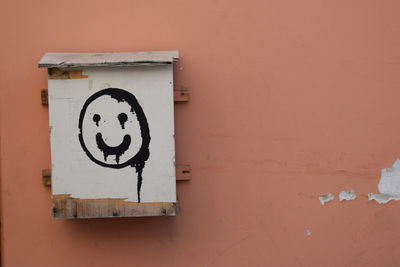 Close-up of information sign and smily on wall