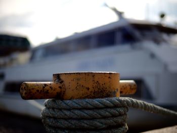 Close-up of mooring bollard with boat in background at harbor