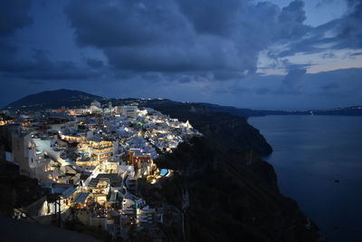 High angle view of illuminated city by sea