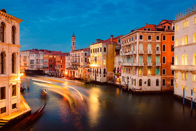 Venice's grand canal at sunset with illuminated historic buildings and light trails of tourist boats