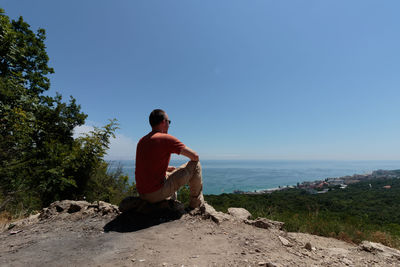 Rear view of man looking at sea against sky