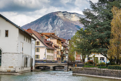 Houses by buildings and mountains against sky