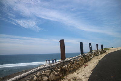 Wooden posts on beach against sky