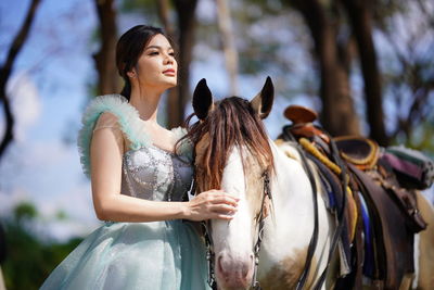 Portrait of a beautiful woman with a horse in the forest background.