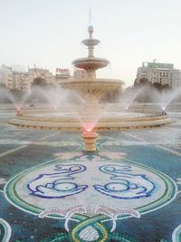 Fountain in city against clear sky