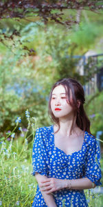 Portrait of young woman standing against plants