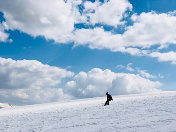 Woman snowboarding on snowcapped mountain against sky