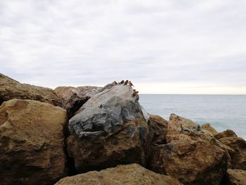 Scenic view of sea by rocks against sky