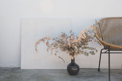 Close-up of flower vase on table against wall at home