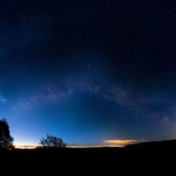 Silhouette landscape against star field at night