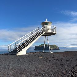 Lighthouse by sea against sky