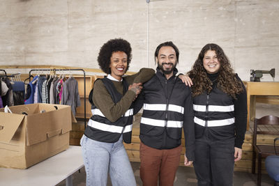 Portrait of happy male and female workers wearing reflective vest at standing at recycling center