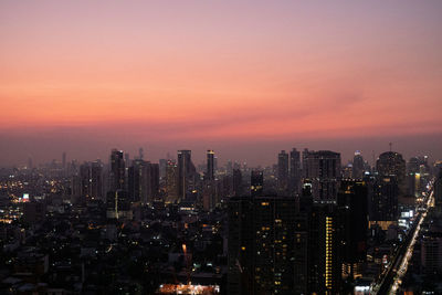 Aerial view of illuminated city against sky during sunset