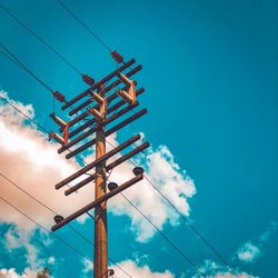 Low angle view of electricity pylon against blue sky