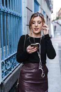 Young woman using mobile phone while standing on camera