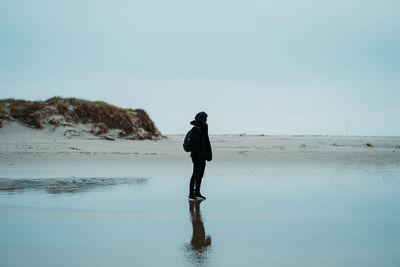 Full length of man standing on beach against clear sky