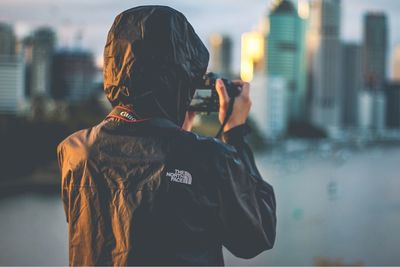 Rear view of person standing against sky in city