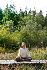 Full length of woman sitting on land against trees