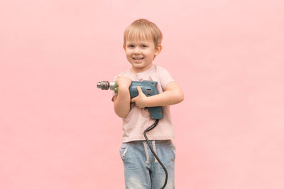 Portrait of boy standing against pink background