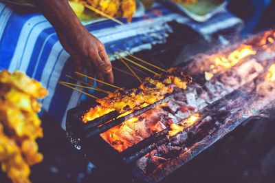 Cropped image of hand cooking satay on barbecue