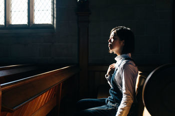 Side view of woman looking away while sitting in church