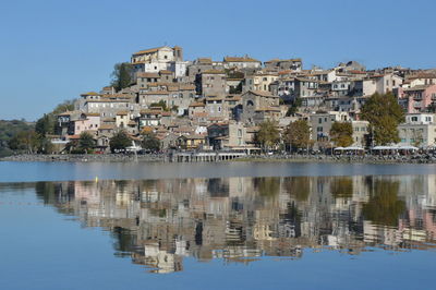 Reflection of buildings in lake against blue sky