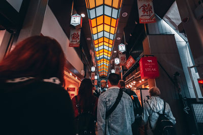 Rear view of people walking in illuminated city