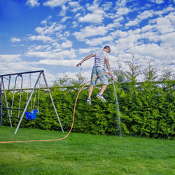 Boy playing with plants against sky