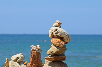 Stack of rocks against sea against clear sky