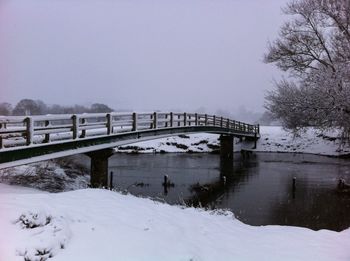 Bridge over river against sky during winter