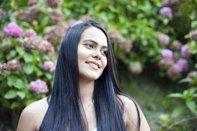 Portrait of smiling happy young latin american woman, isolated background of trees and flowers. 