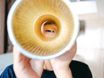 Close-up view of a boy peeping through a yellow cone