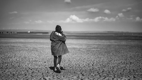 Rear view of woman standing on field against sky