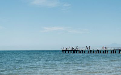 People in sea against clear sky