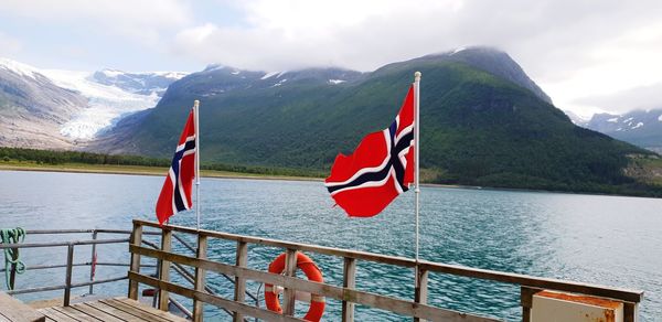 Scenic view of flag by lake against mountains