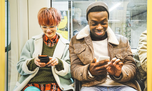 Young woman using smart phone while sitting on laptop