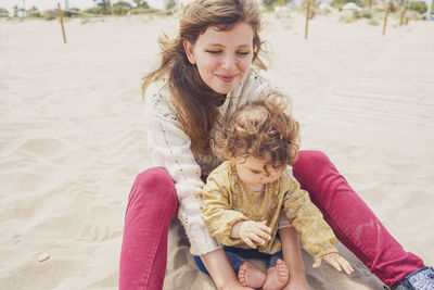 Full length of happy woman sitting on beach