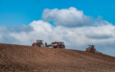 Tractors on agricultural field against sky