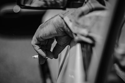 Close-up black and white view of a man smoking, driving, waiting for traffic end. 