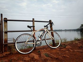 Bicycle on field by lake against sky